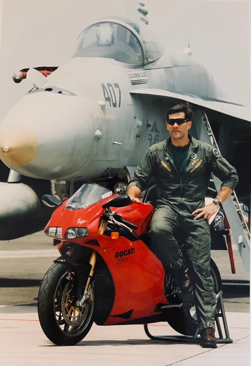 Boss Russ Bartlett leaning on motorcycle with jet behind him